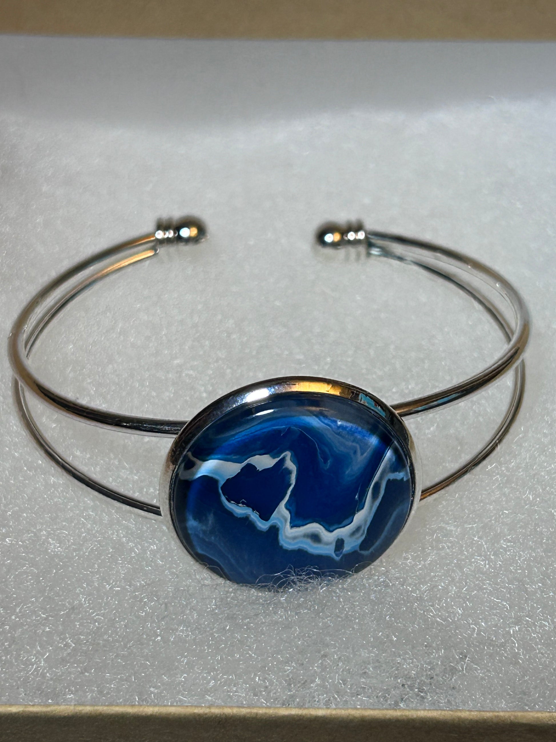Silver bracelet with a blue marbled art on a light gray background