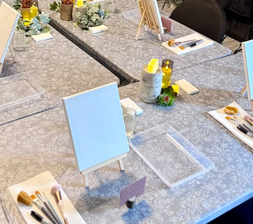 Table setup with art supplies and stationery items in a room.